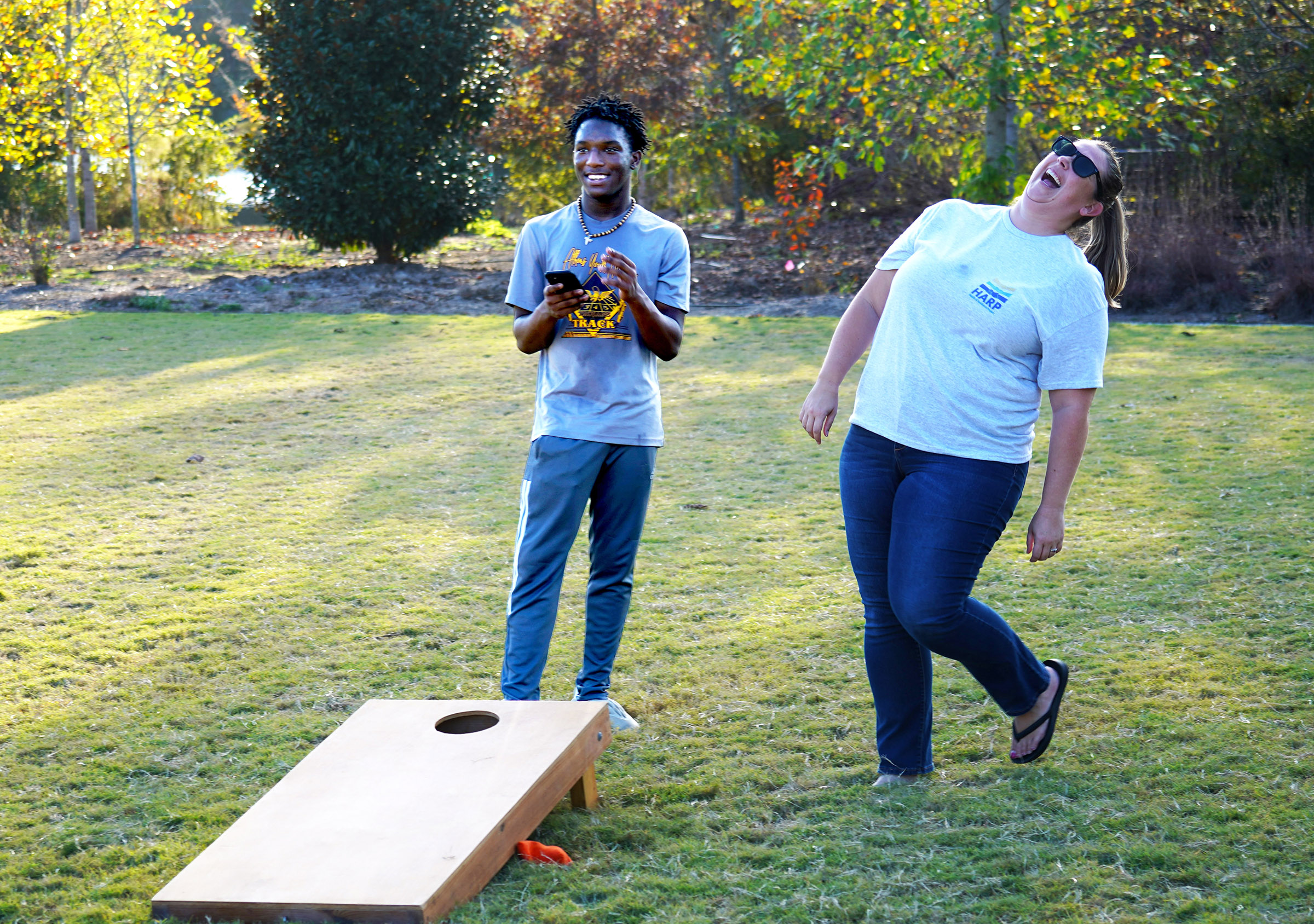 Woman and teen boy playing corn hole and laughing