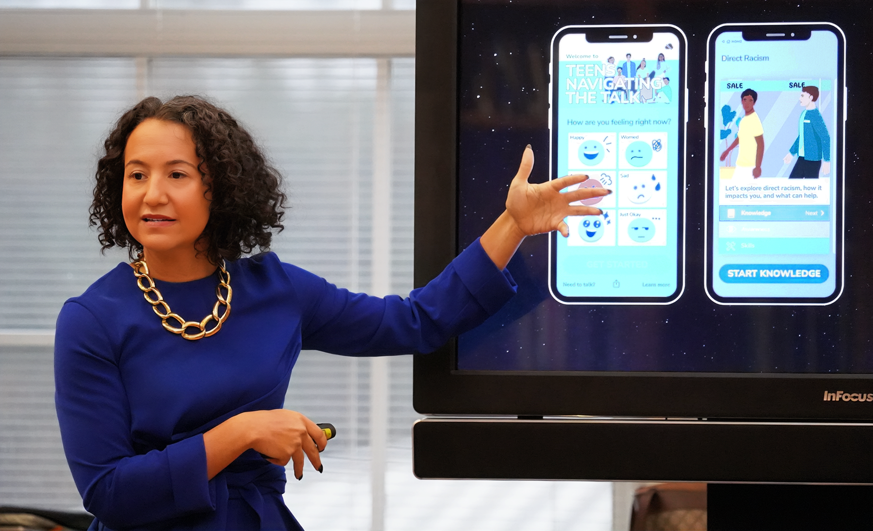 Riana_Anderson_app2 Woman speaking and gesturing to images on a screen.